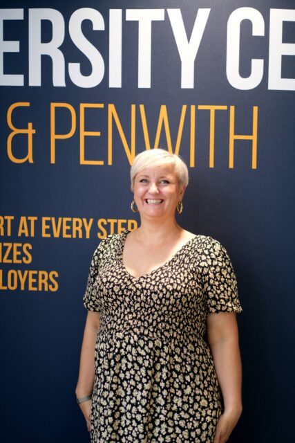 Tasha stood smiling in front on University Centre banner