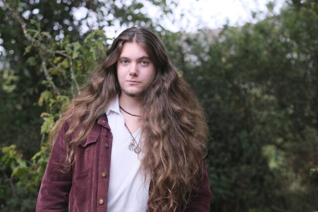 Tom stood smiling in front of trees