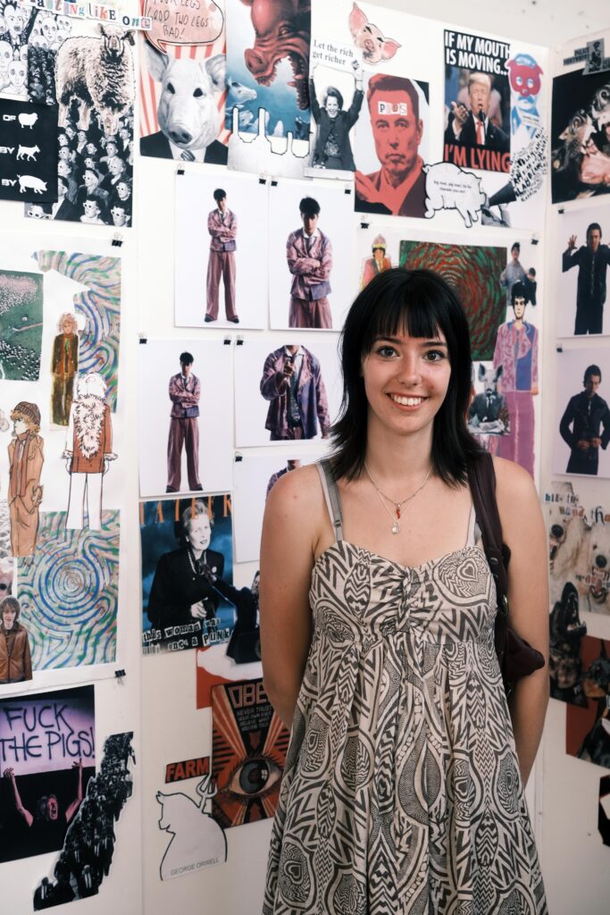 Lottie stood smiling in front of a collection of her artwork.