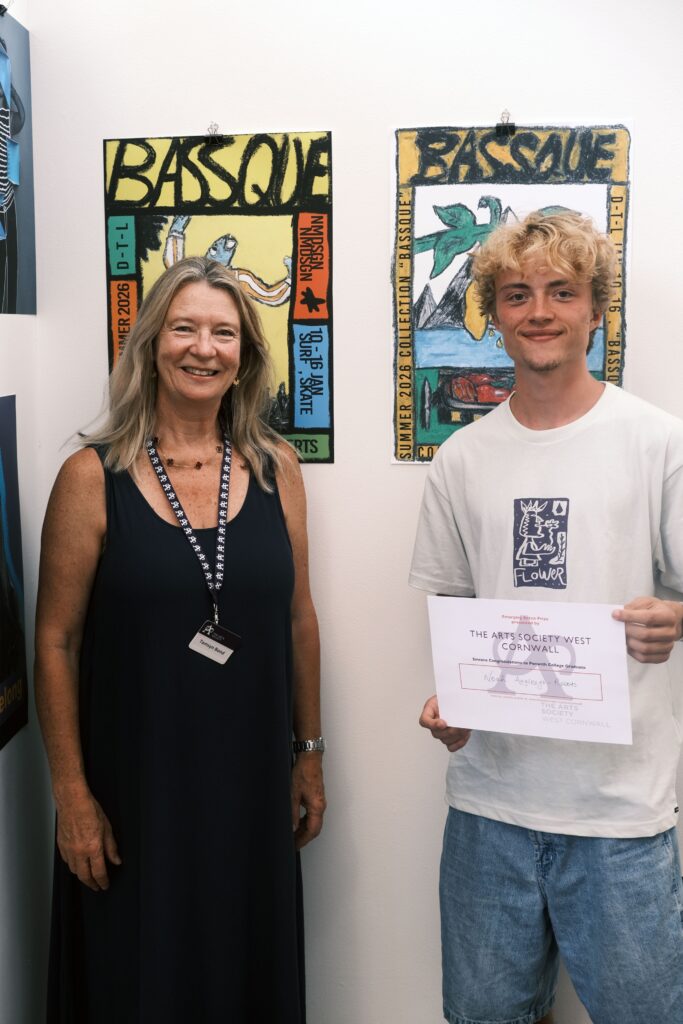 Noah (R) stood smiling, holding a certificate with a representative of the Art Society West Cornwall (L)