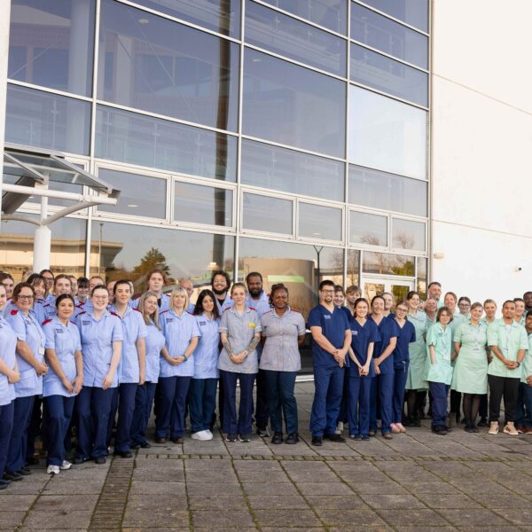 Large group of student nurses, in uniform, stood outside.