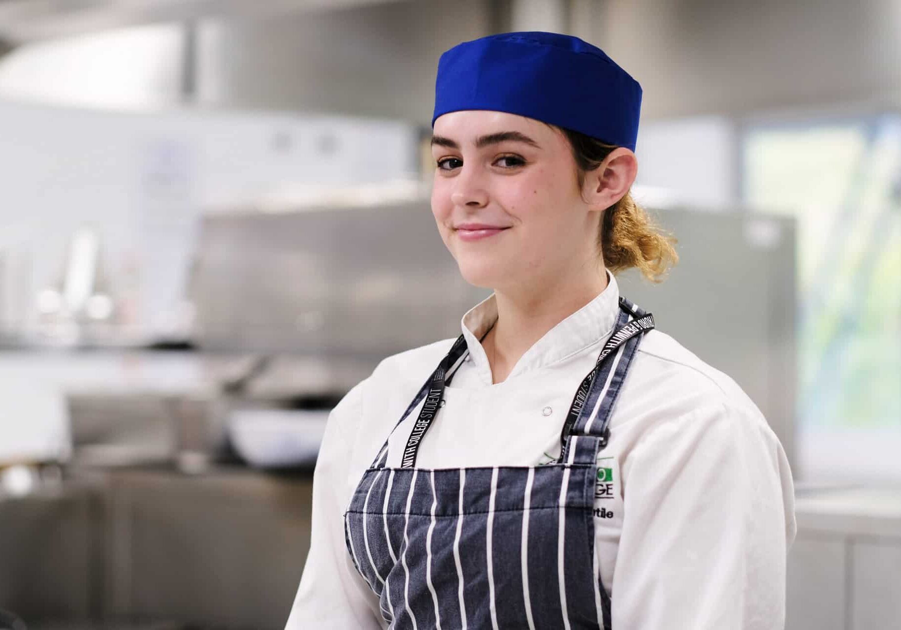 Lottie Level 2 Diploma in Professional Cookery at Truro and Penwith College. Lottie is dressed in professional chef wear in one of the College's working kitchens.